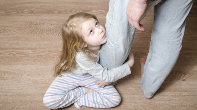 Young girl hugging her father's leg