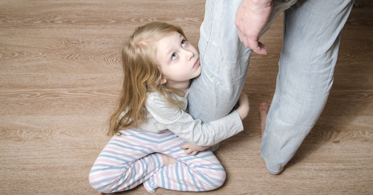 Young girl hugging her father's leg