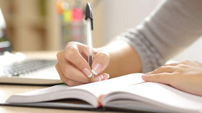 Woman hand writing in an agenda at home