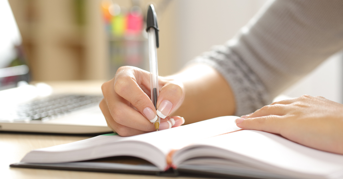 Woman hand writing in an agenda at home