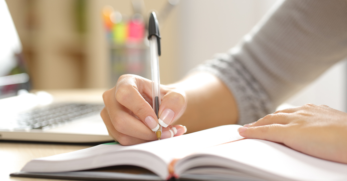 Woman hand writing in an agenda at home