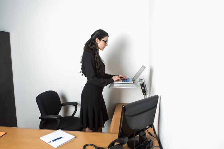 Young pretty business woman standing up using computer in the office