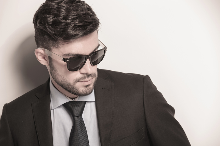 sexy young business man wearing sunglasses looks away