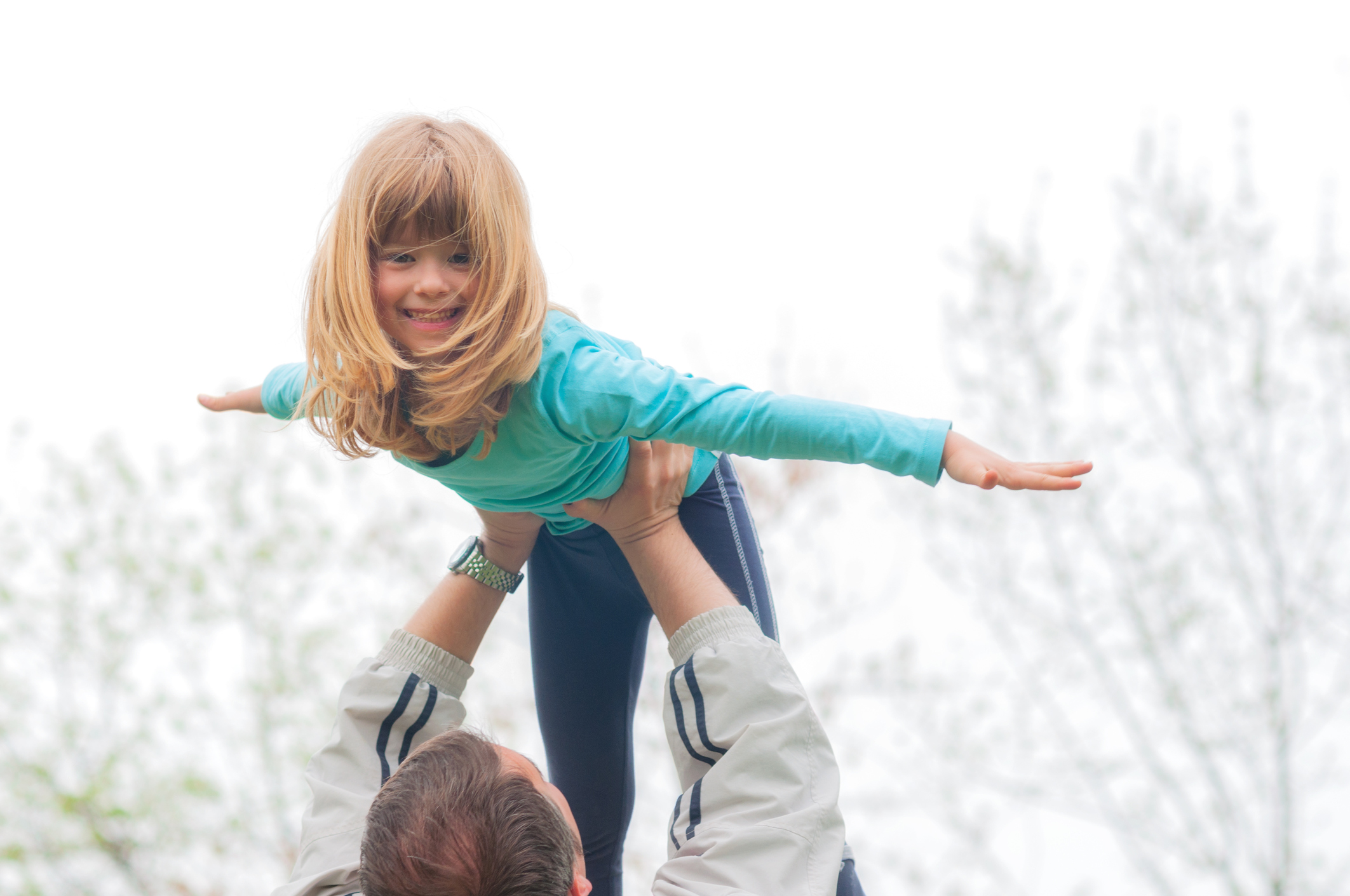 Little girl lifted in air by her father