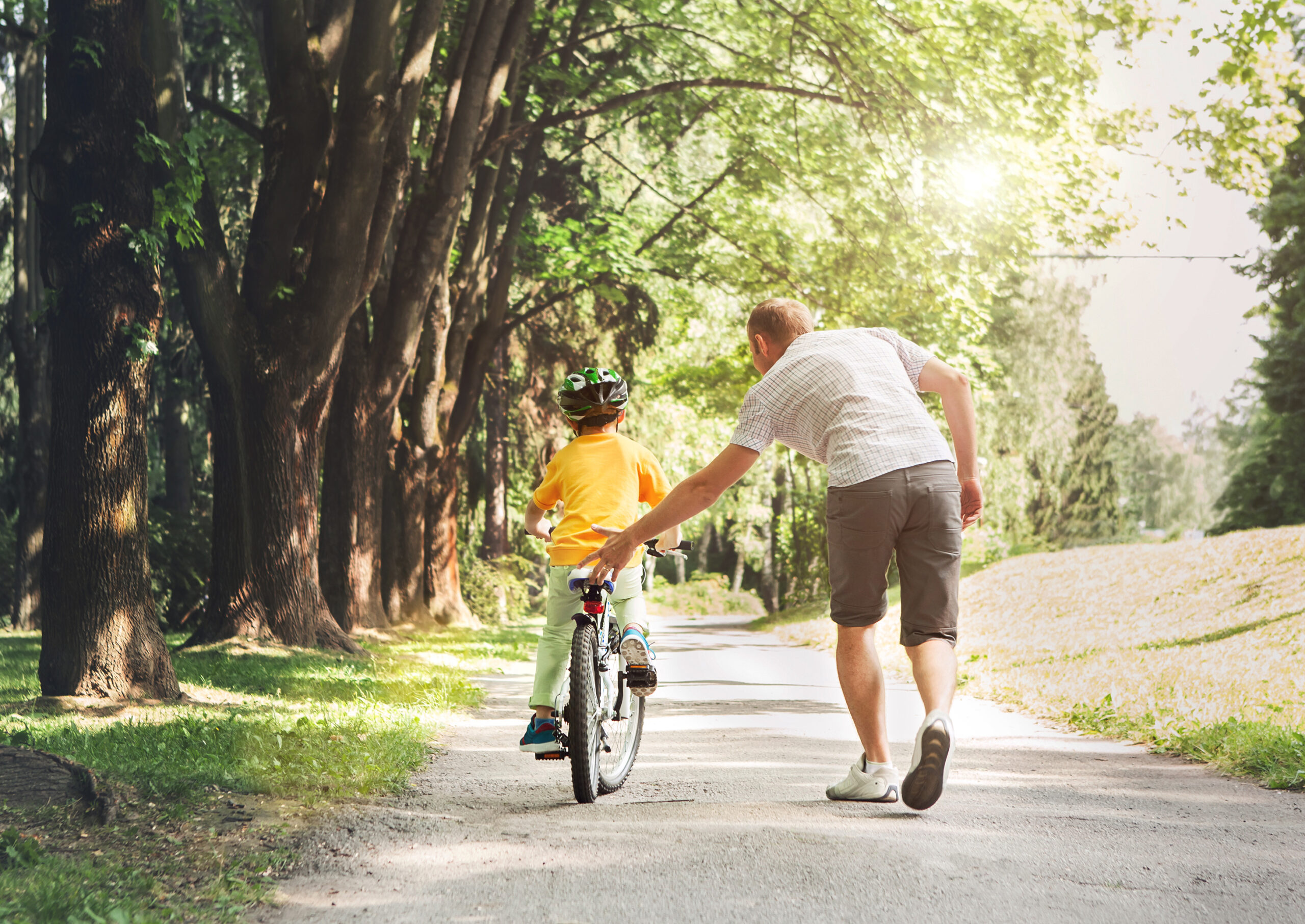 Father help his son ride a bicycle