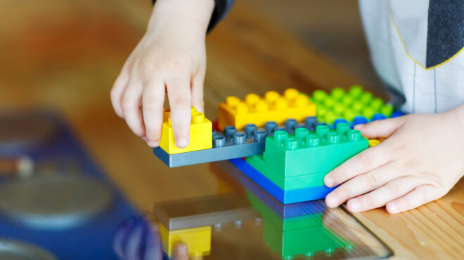 Hand child playing with construction blocks