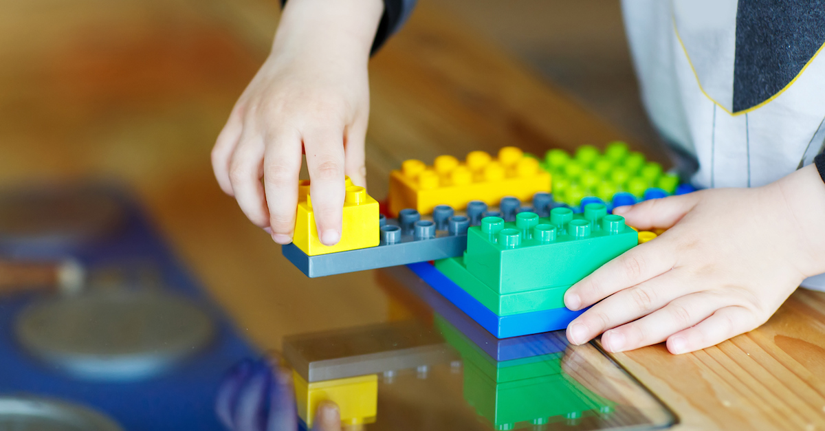 Hand child playing with construction blocks