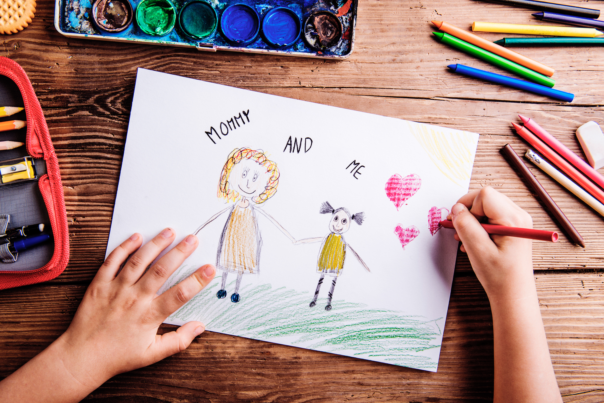 Unrecognizable girl drawing picture of her and her mother