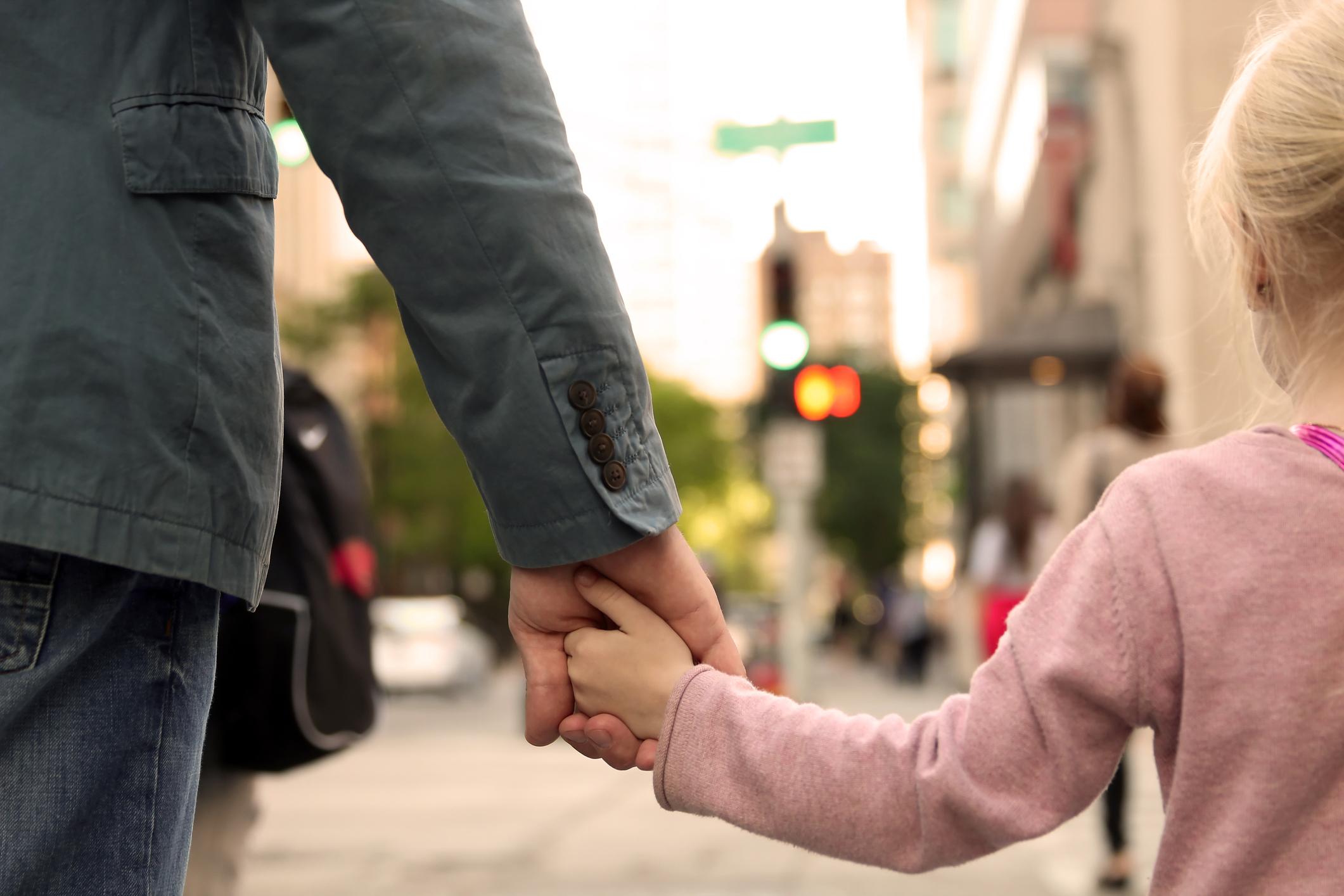 father holding  the daughter/ child  hand  behind  the traffic lights