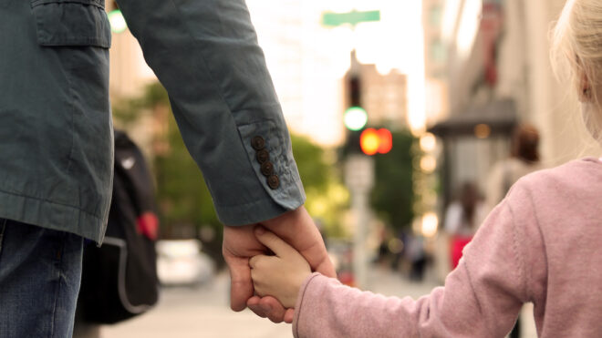 father holding  the daughter/ child  hand  behind  the traffic lights