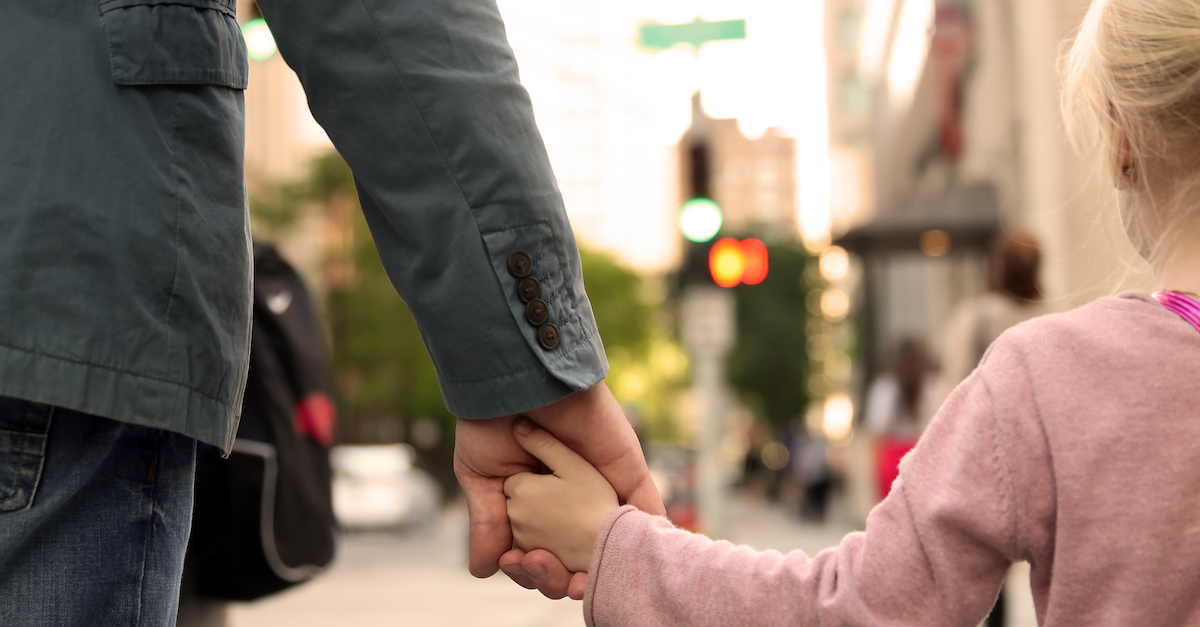 father holding  the daughter/ child  hand  behind  the traffic lights