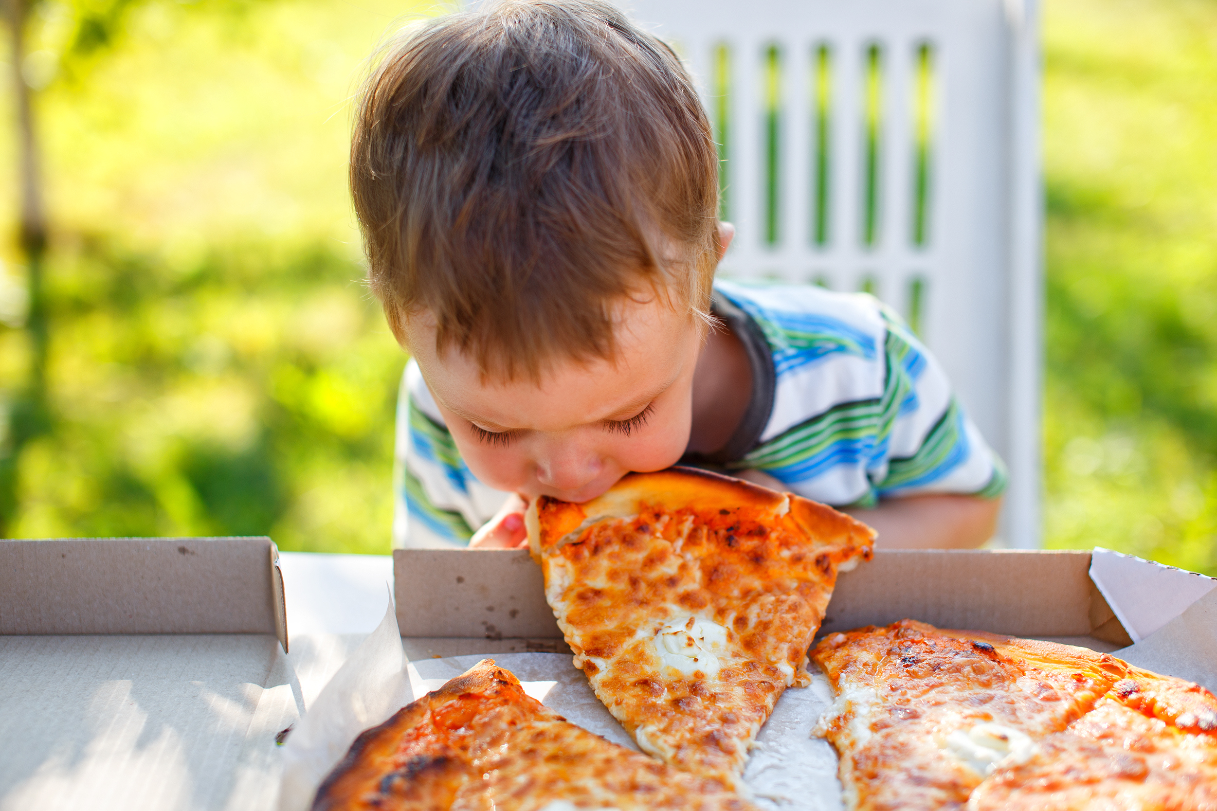 kid biting a slice of pizza