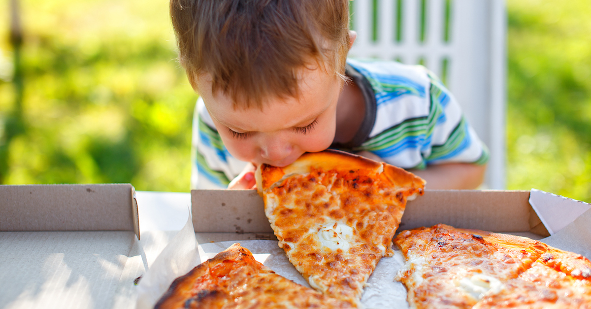 kid biting a slice of pizza