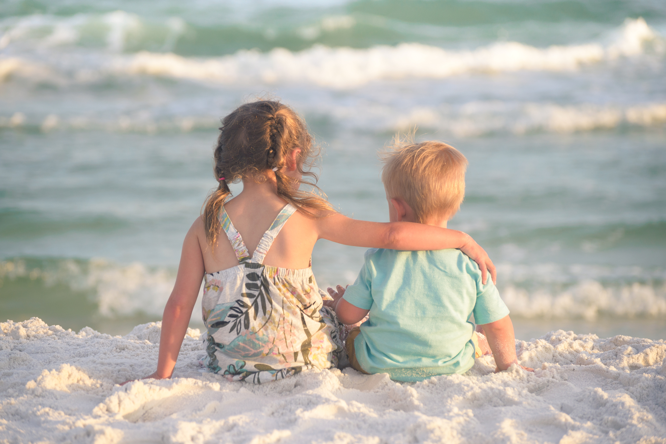 Sister and brother hugging on the beach