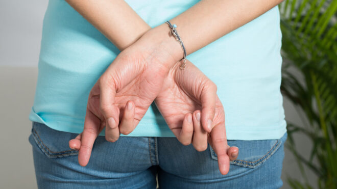 Midsection Of Woman With Fingers Crossed