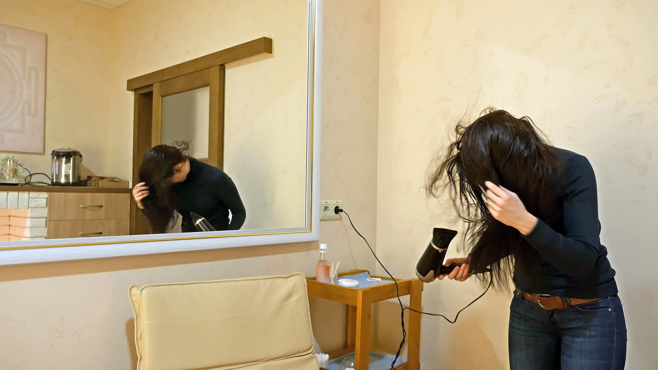 Pretty woman drying long hair in make-up room