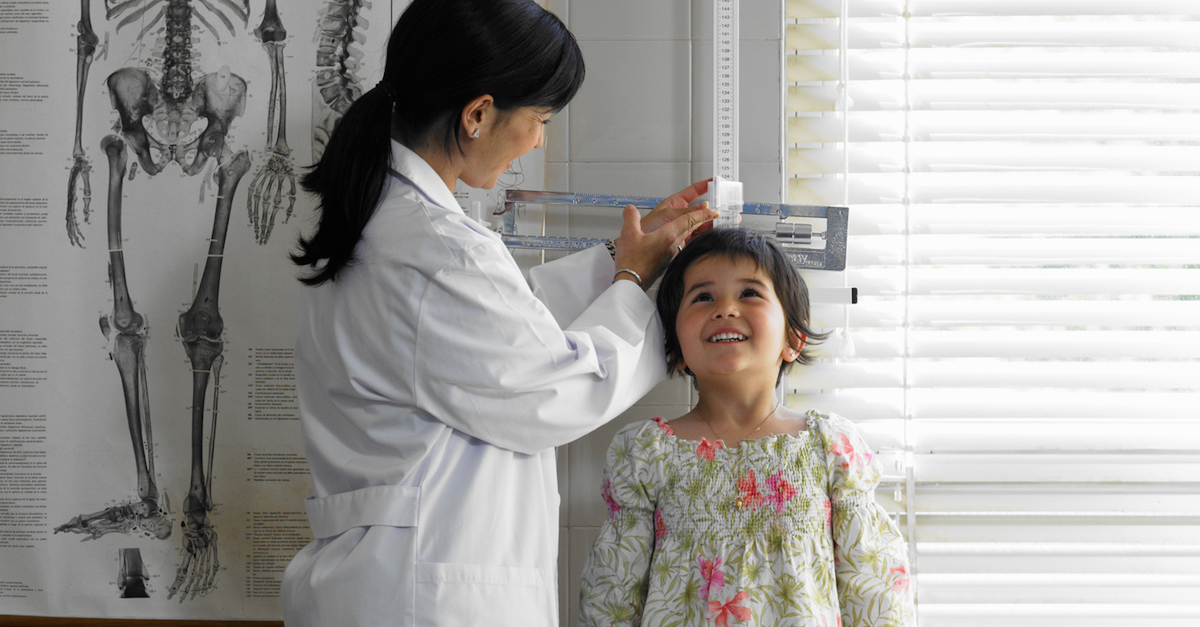 Doctor measuring girl (5-7 years) in examination room