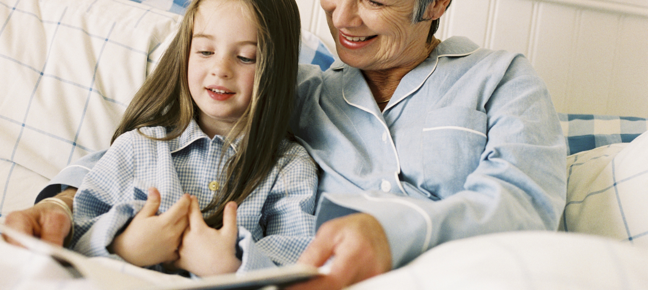 Grandmother and granddaughter reading in bed