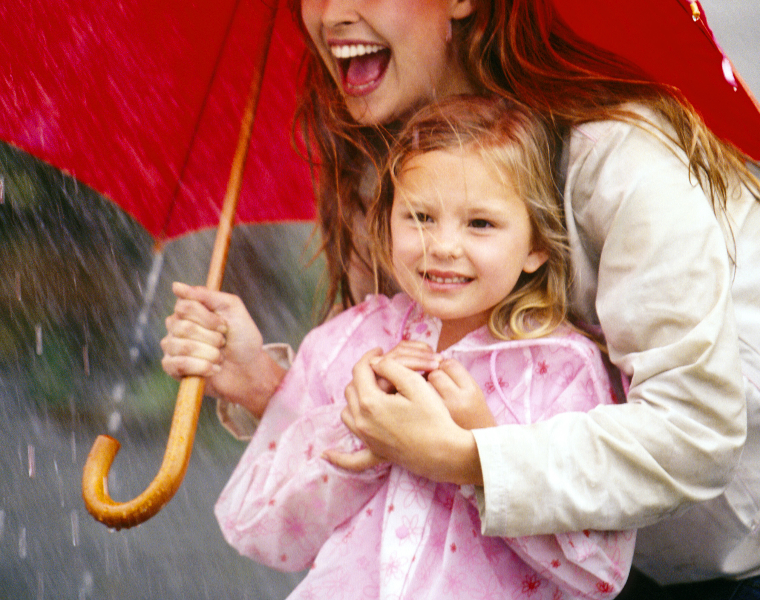 Mother and daughter laughing under umbrella