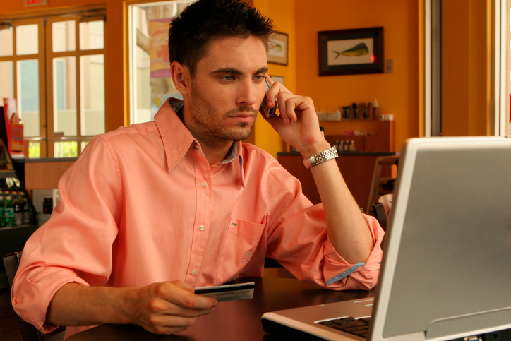 Young man talking on a mobile phone holding a credit card