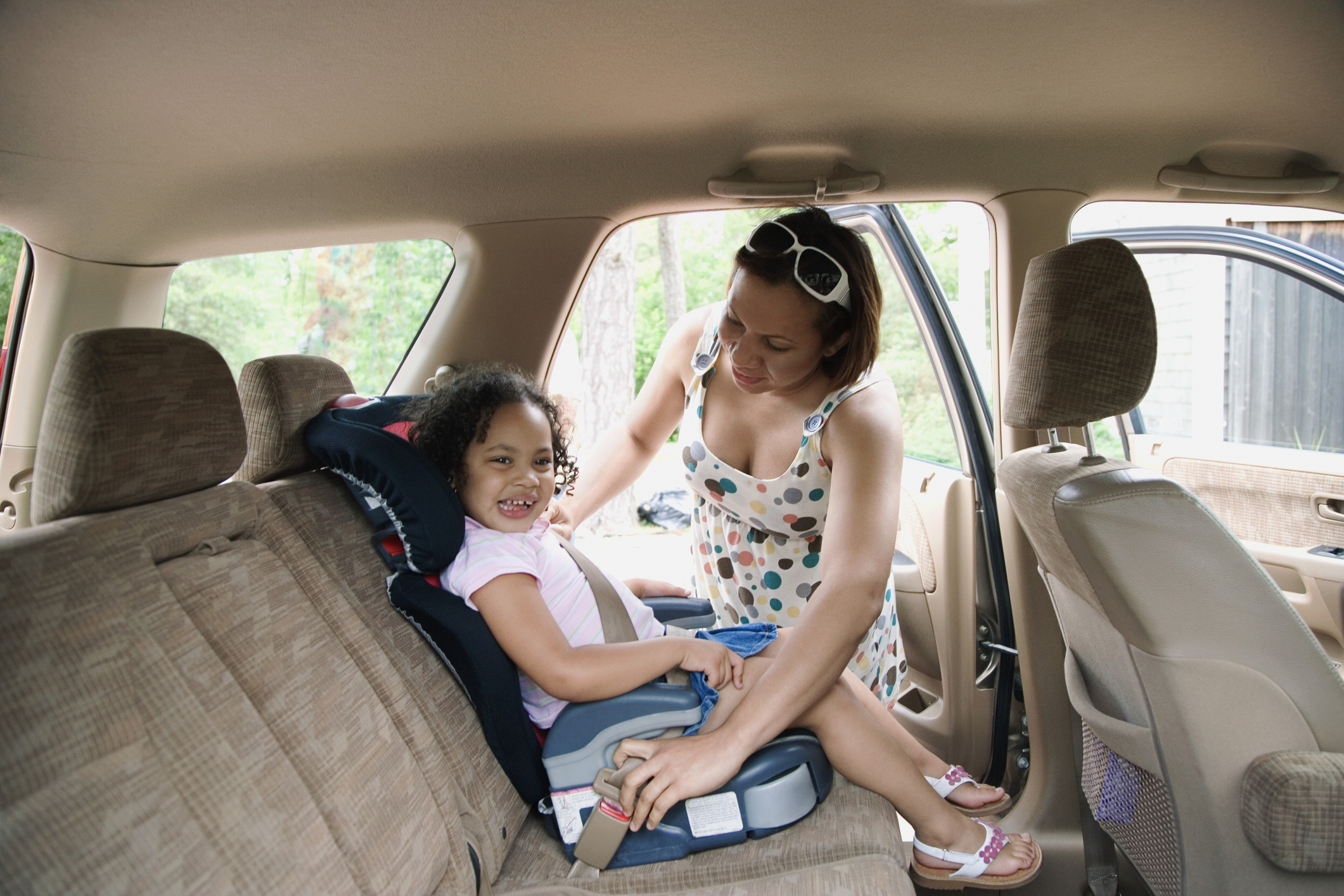 Mother putting daughter in car seat