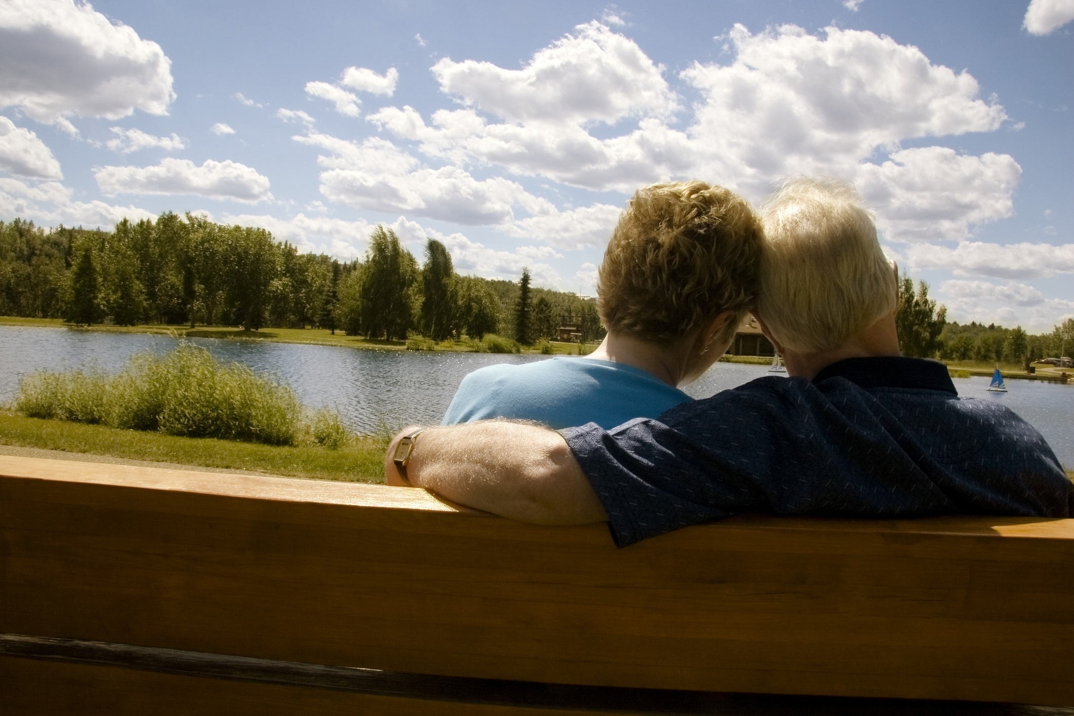 Married couple sitting on lakefront bench