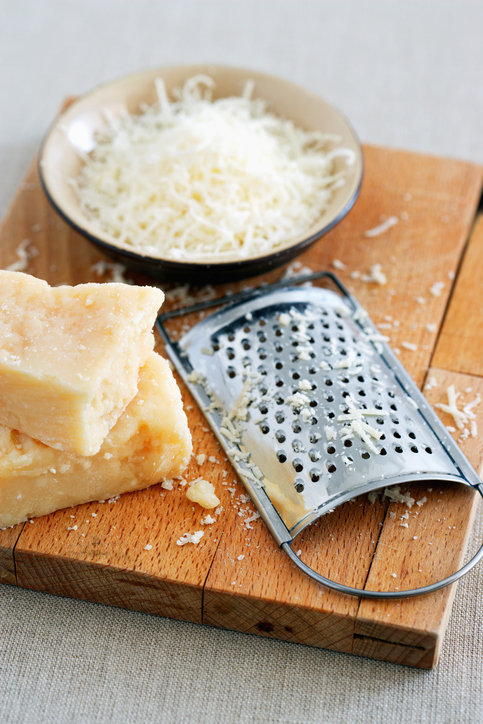 Parmesan cheese and grater on cutting board at table