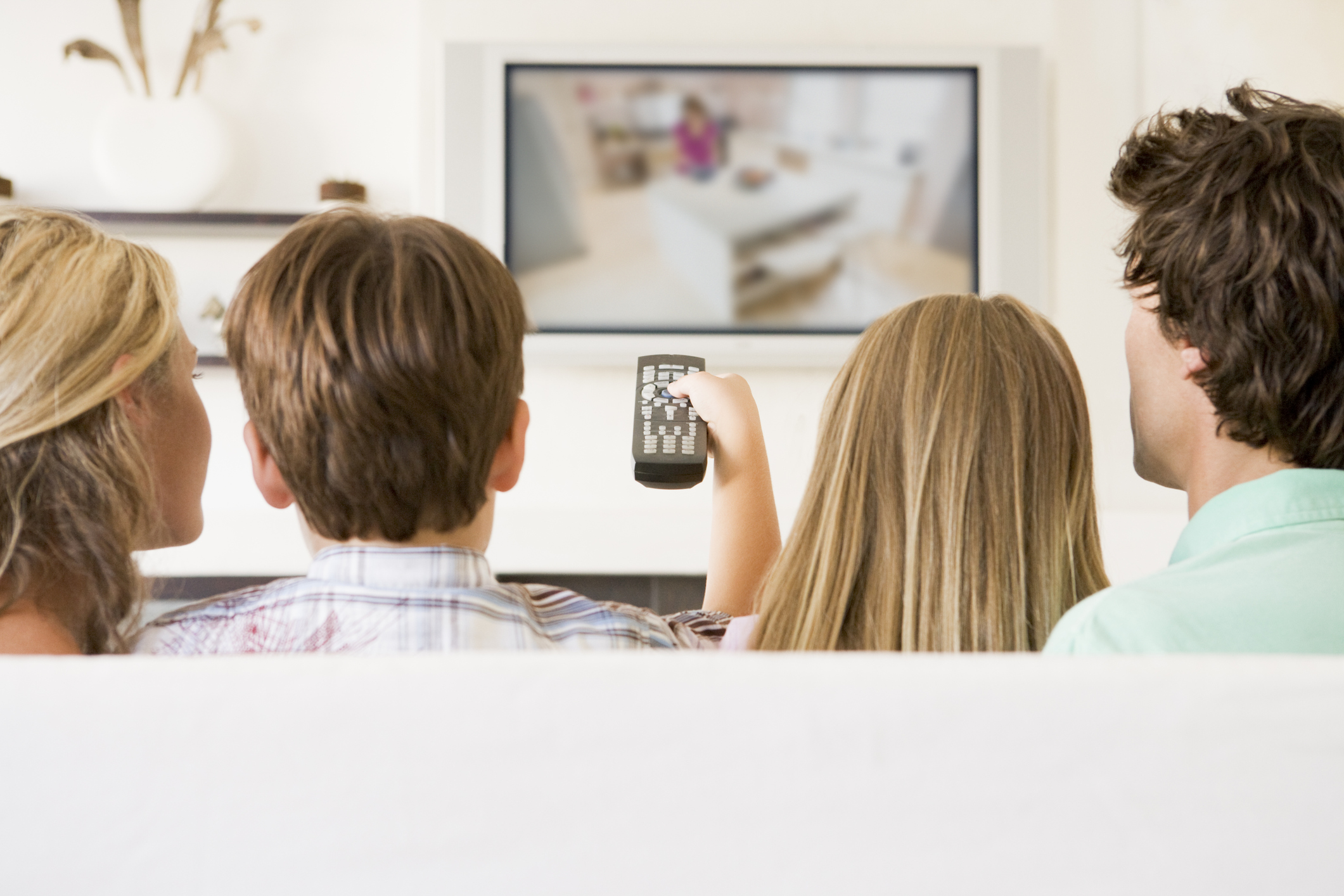 Family in living room with remote control and flat screen television