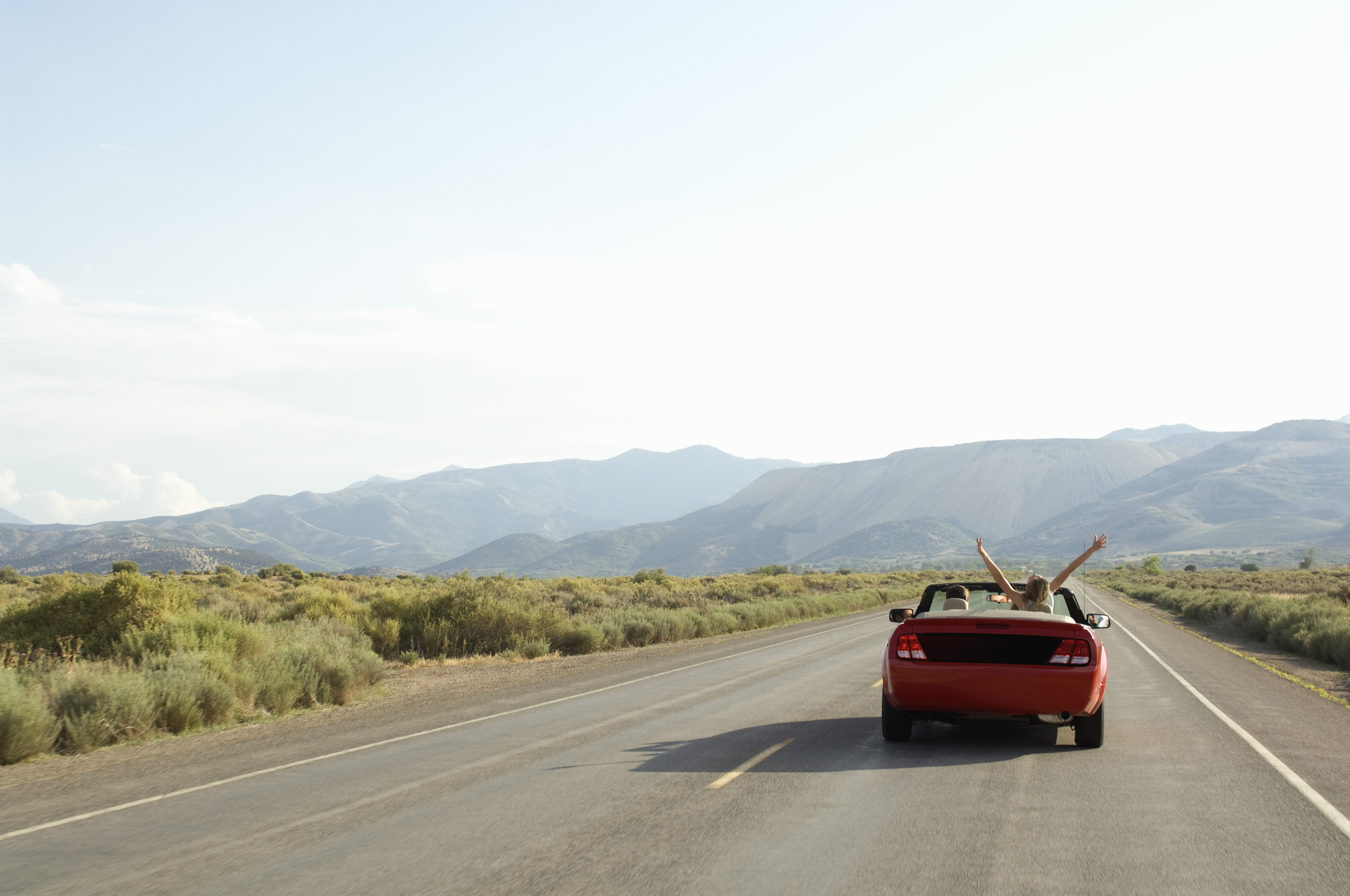 Carefree couple driving convertible on desert road Carefree couple driving convertible on desert road