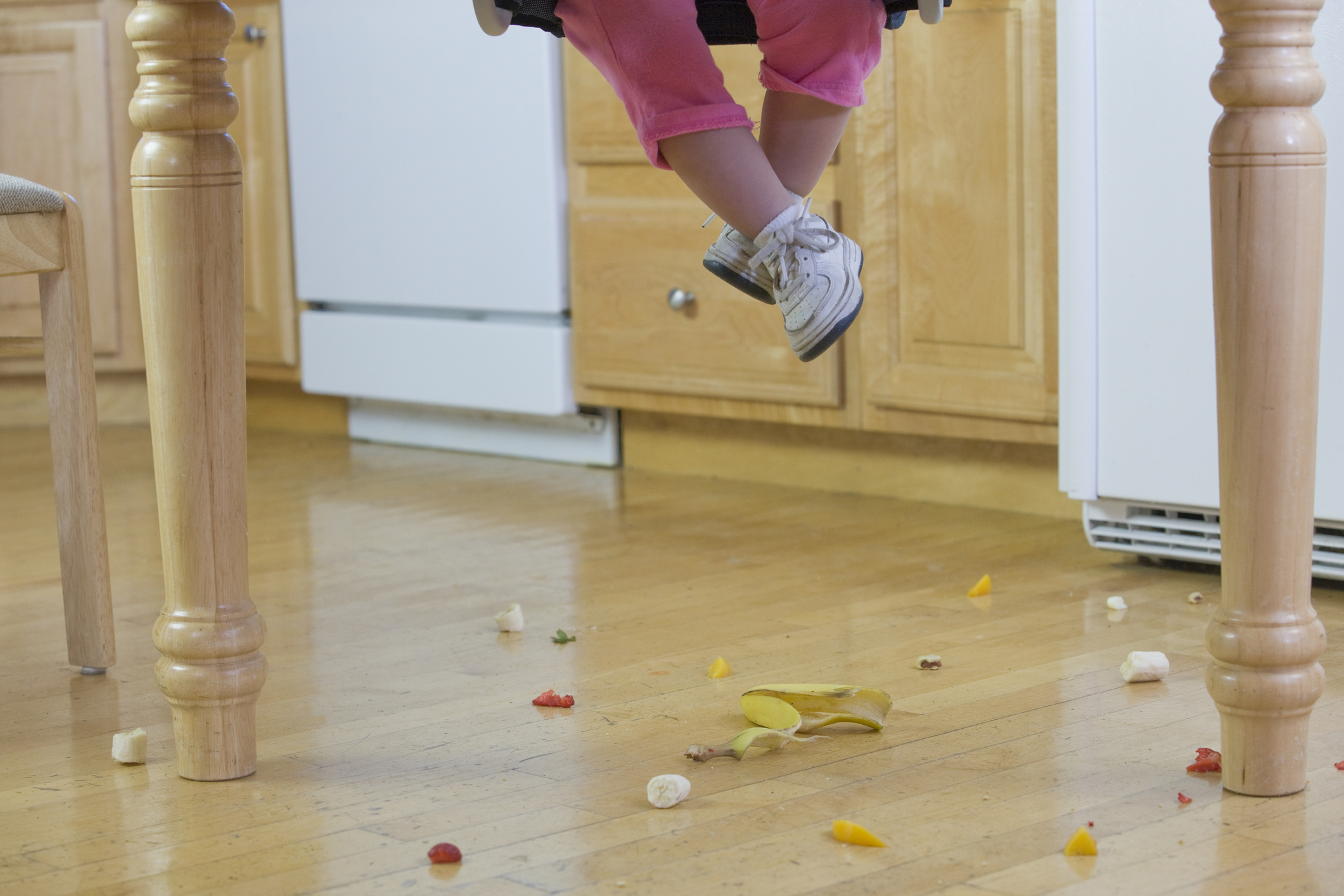 Low section view of a baby girl with spilled food on the floor