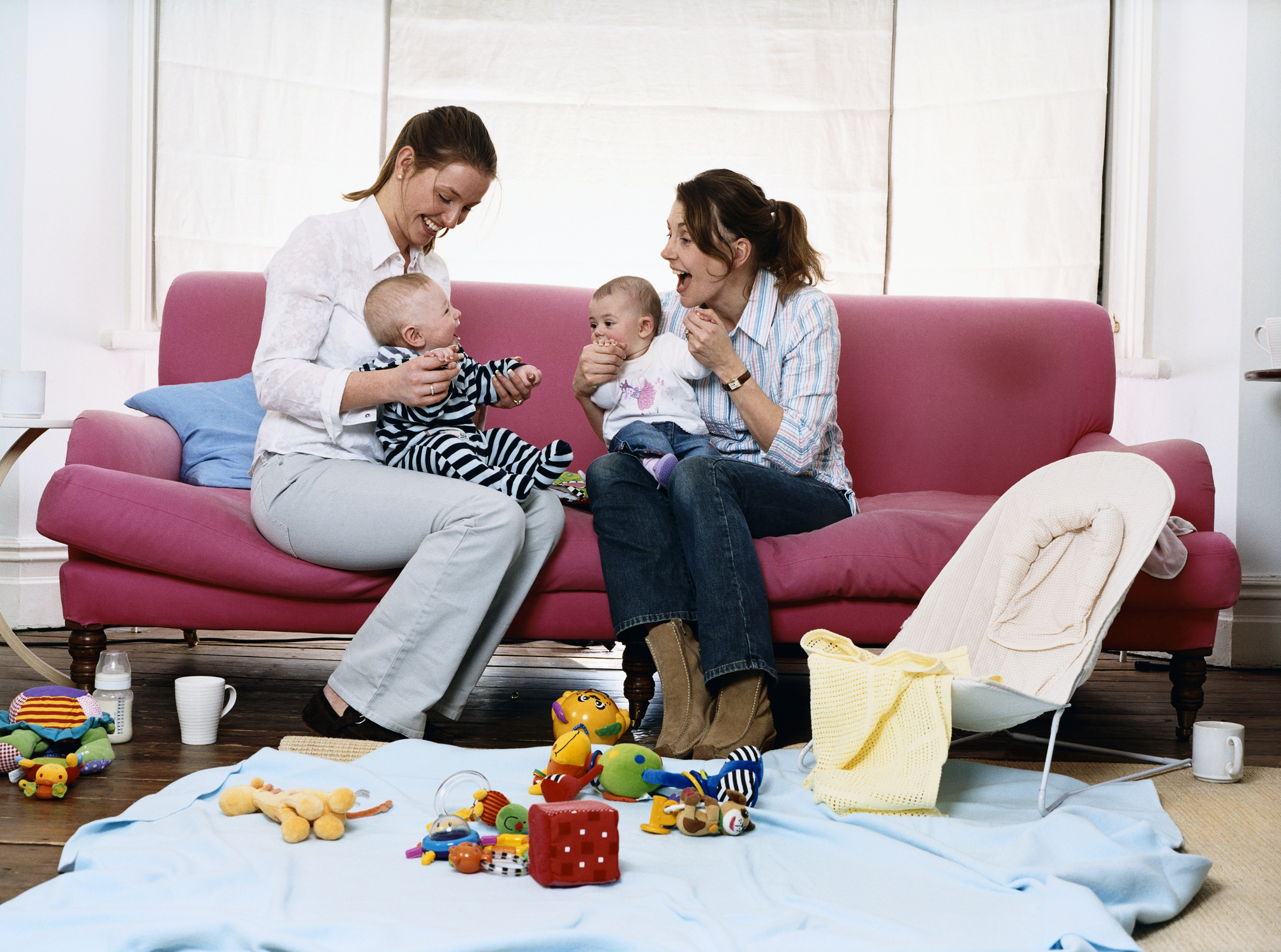 Mothers on a Sofa in a Living Room With Their Babies