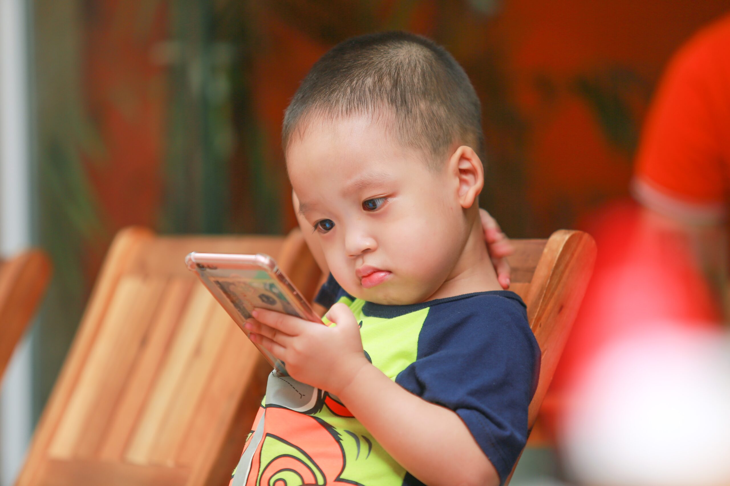 boy-holding-smartphone-siting-on-chair-2181423.jpg