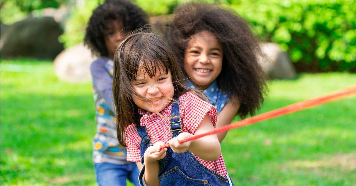 Happy children playing tug of war in the park.