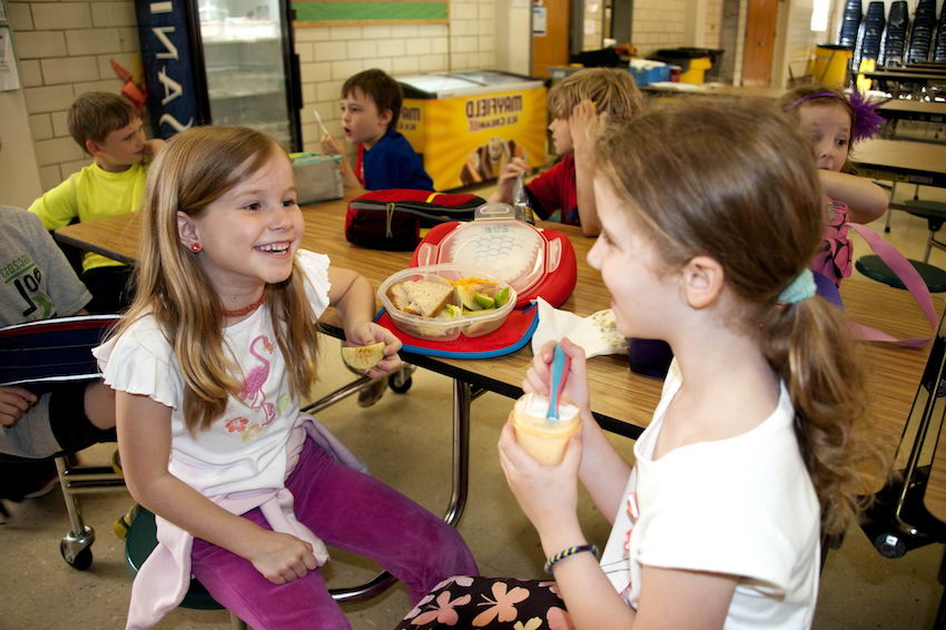 Girl on the left was eating a small serving of what appeared to be vanilla yogurt