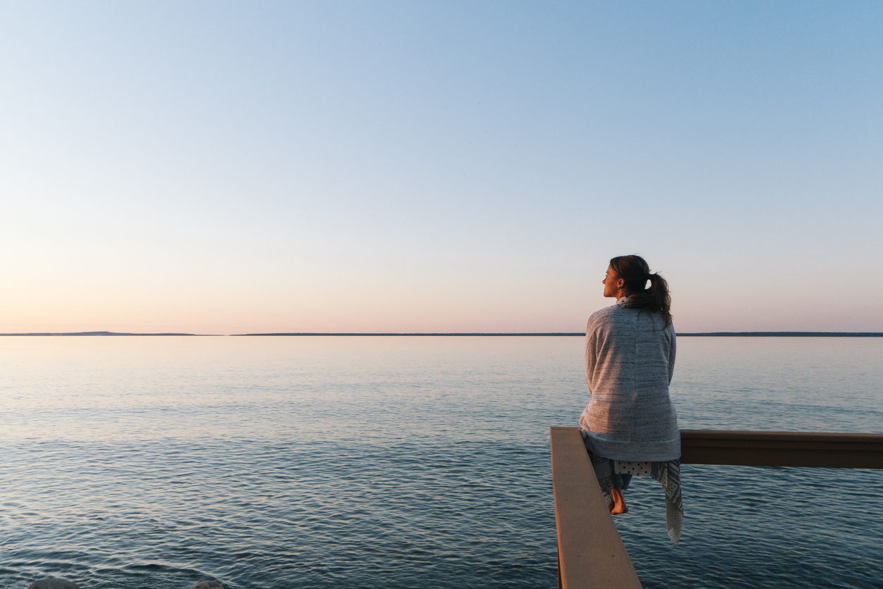 Young woman sitting on edge looks out at view