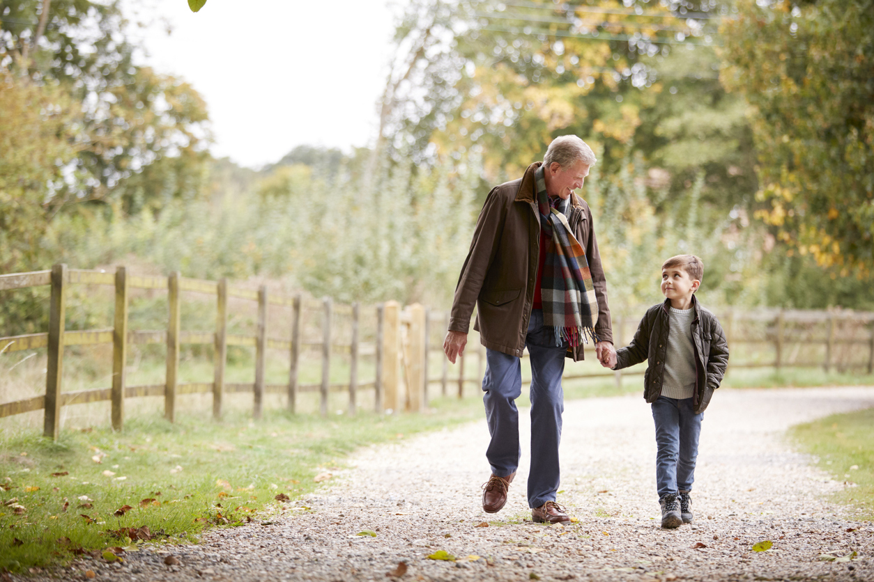 Grandfather With Grandson On Autumn Walk In Countryside Together