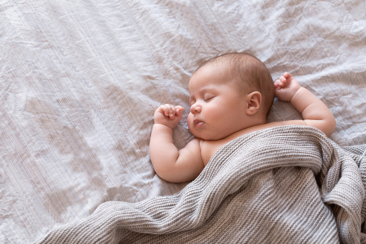 Peaceful baby lying on a bed and sleeping at home