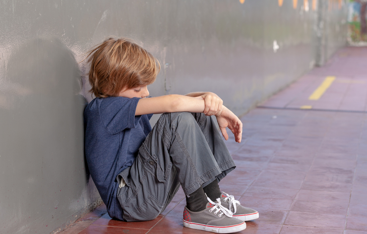 Elementary School. Sad little boy oppressing in the schoolyard. Bullying concept