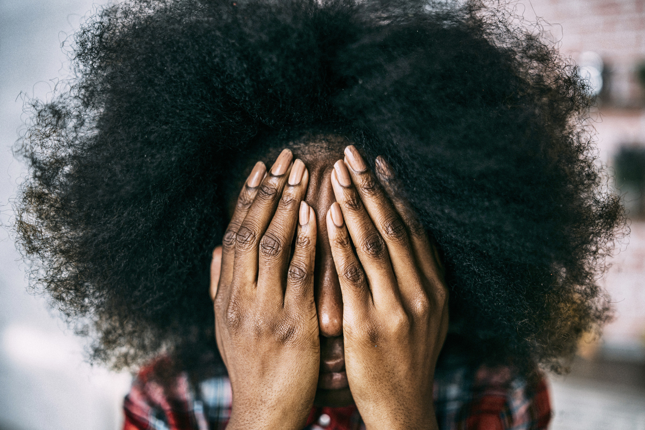African woman sitting at home hands on face
