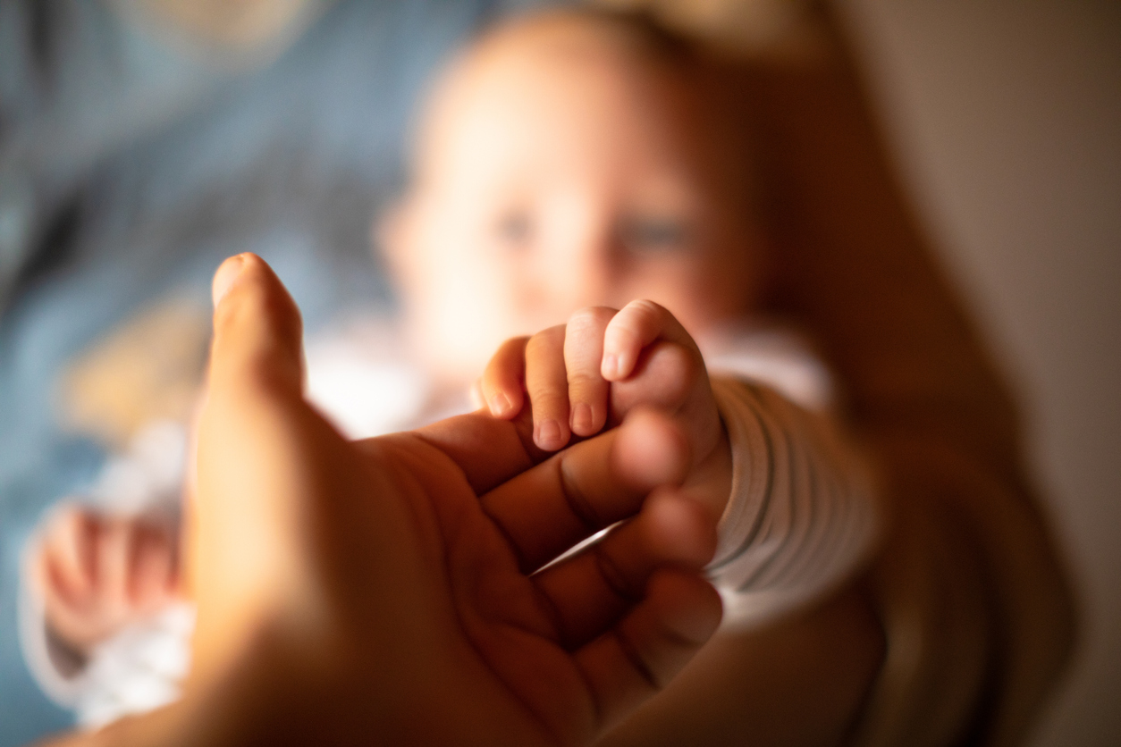 Hand holding newborn baby's hand