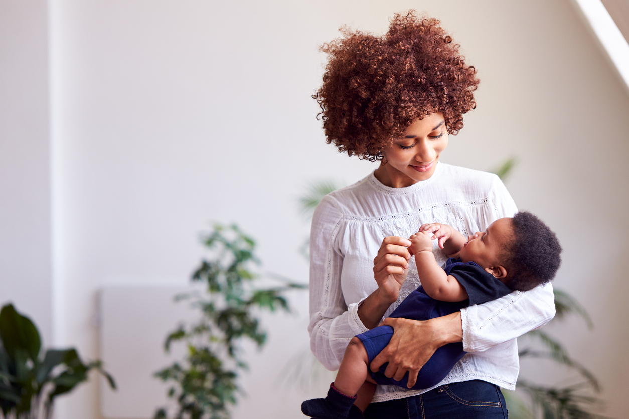 Loving Mother Holding Newborn Baby At Home In Loft Apartment