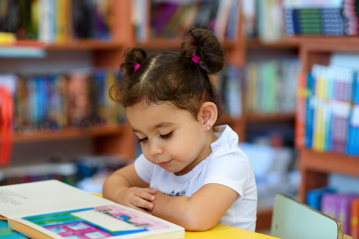 Happy child little girl reading a book.