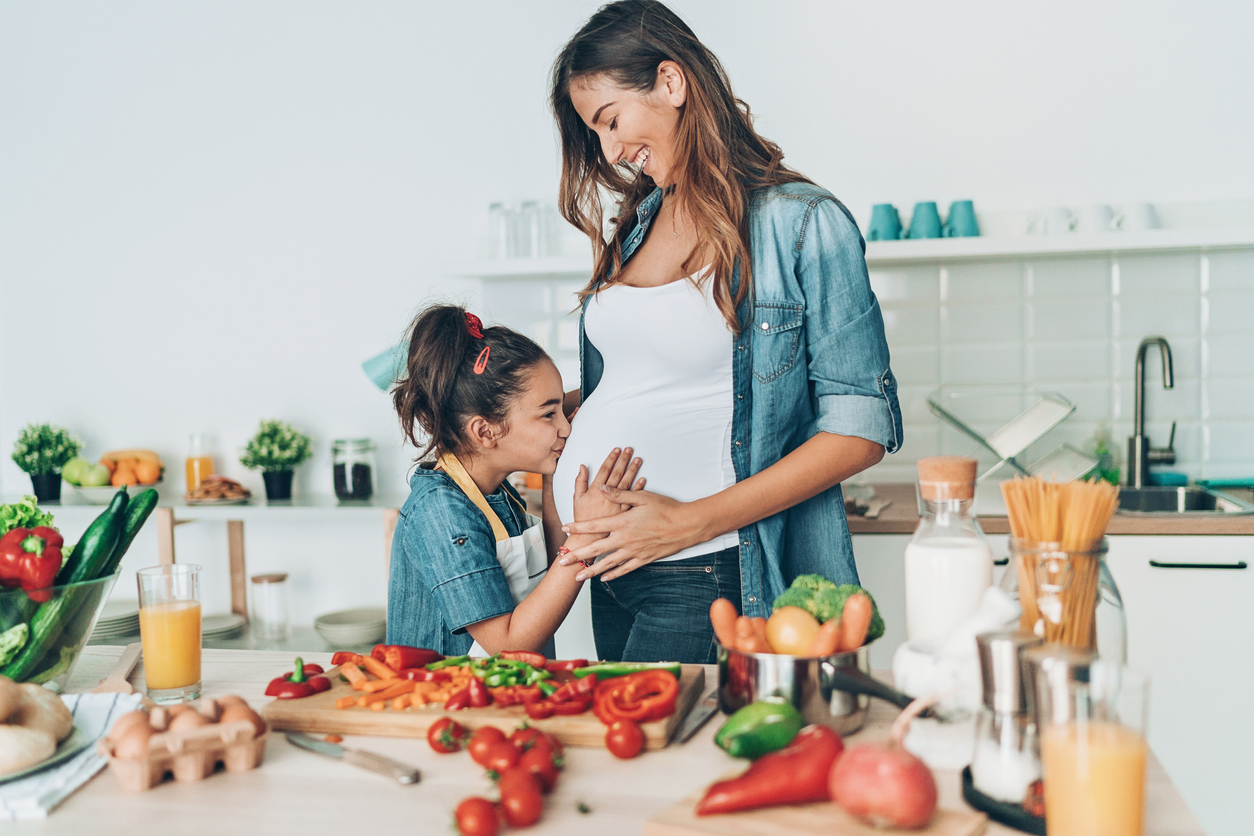 Small girl kissing her pregnant mother