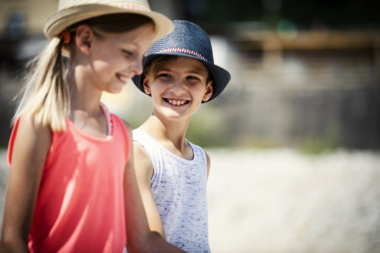 Two cute blond children, brother and sister walking near the river