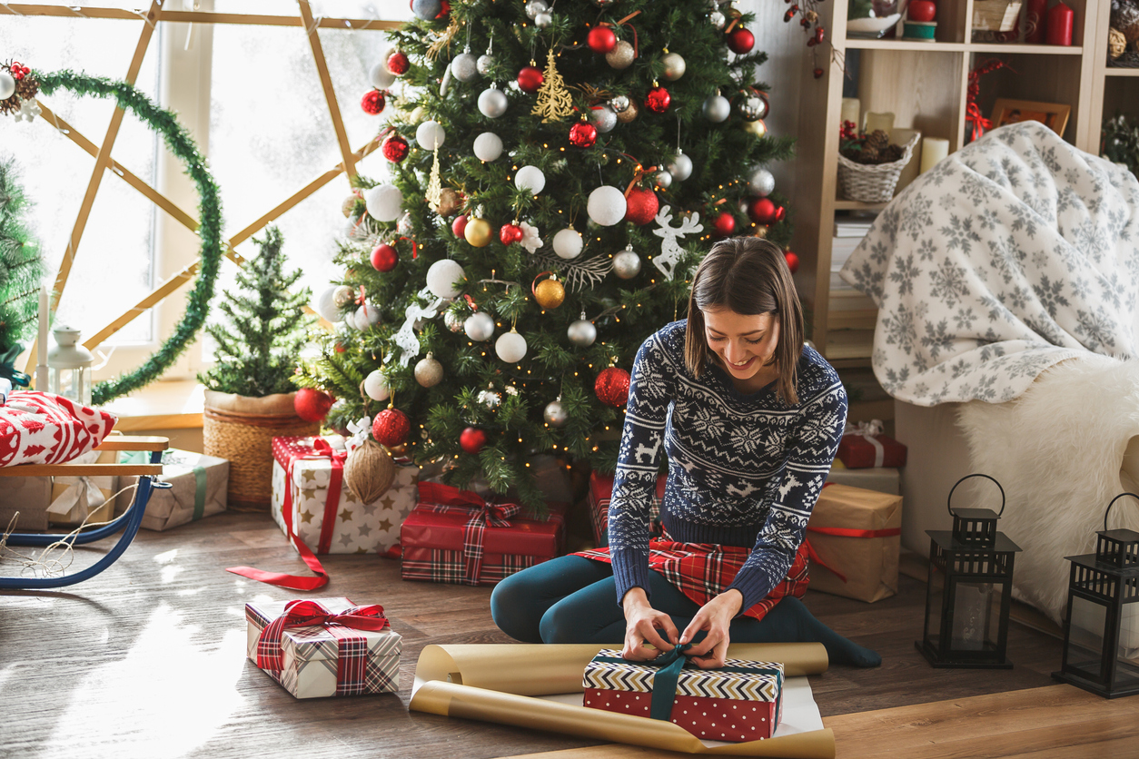 Woman wrapping gifts by the Christmas tree