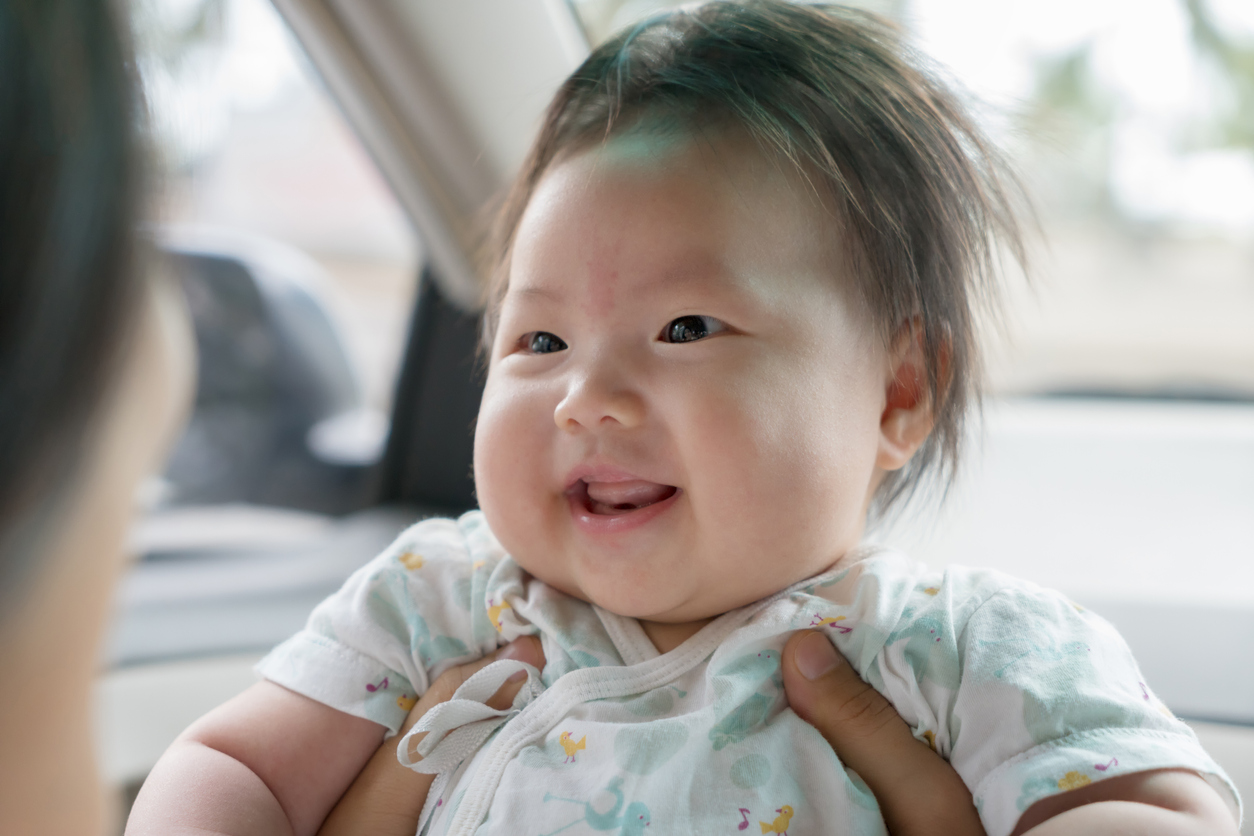 Three month old girl looking at her mother and smiling. baby girl with a birthmark, birthmark on his forehead. Happy family concept