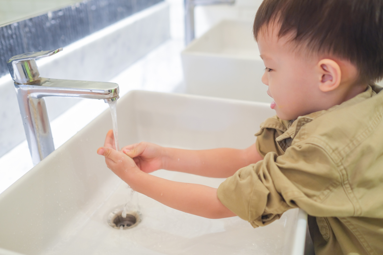 sian 3 - 4 years old toddler baby boy child washing hands by himself on sink and water drop from faucet in public toilet