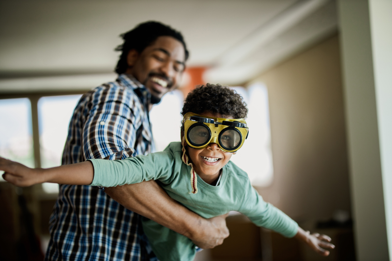 Happy black boy having fun with his father at home.