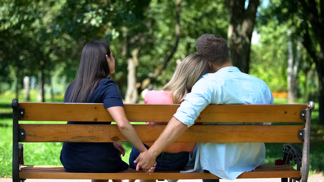 Man hugging woman secretly holding other female hand, secret relations, betrayal