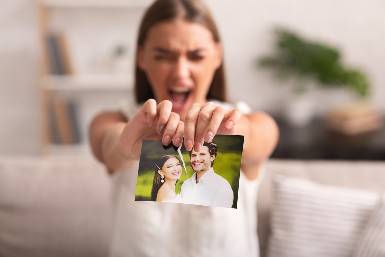 Furious Woman Ripping Wedding Photo Sitting On Sofa Indoor